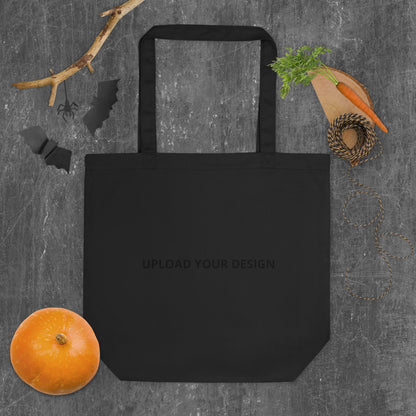 Black organic-cotton tote bag mockup with "Upload Your Design" placement guide, ready for your own custom artwork, Delmas33